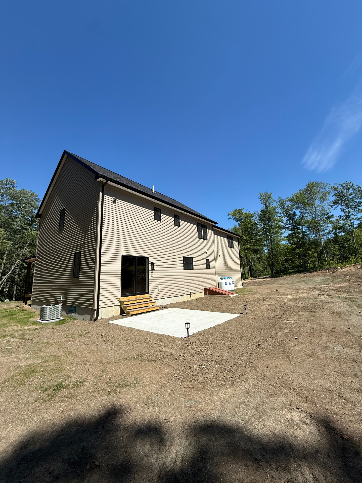 Rear elevation with concrete patio and graded yard
